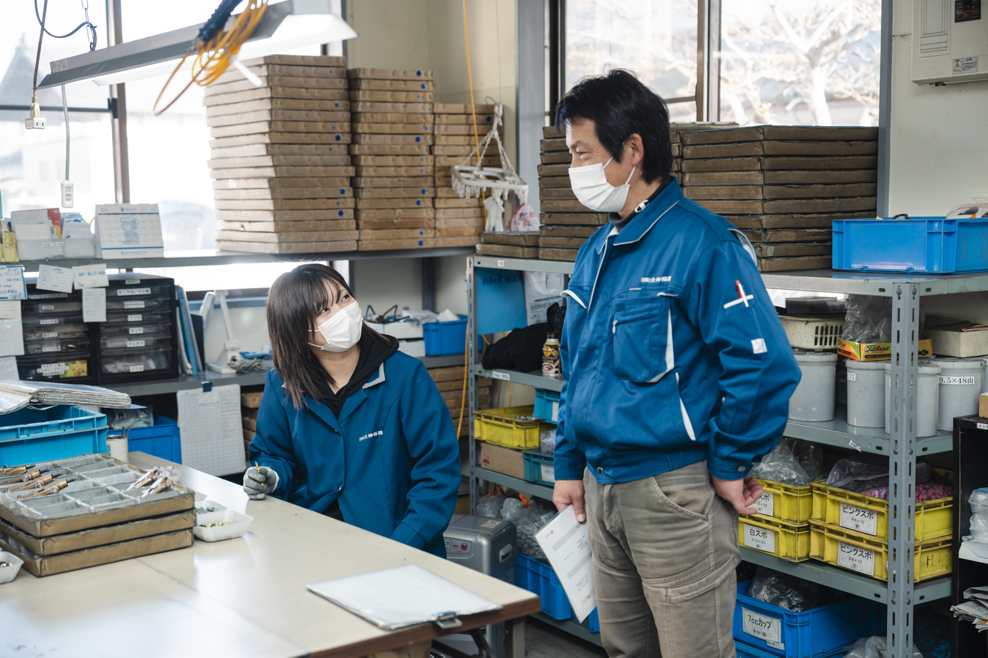 作業場で打ち合わせをする作業服姿の上司と部下